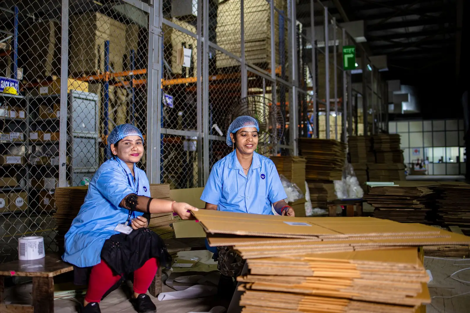 Workers handling corrugated board in a packaging factory